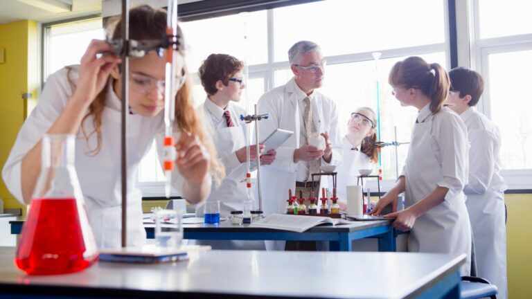 Schülerinnen und Schüler experimentieren mit ihrem Lehrer im Chemieraum