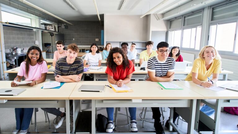 Gut gelaunte Schülerinnen und Schüler an ihren Tischen im Klassenzimmer